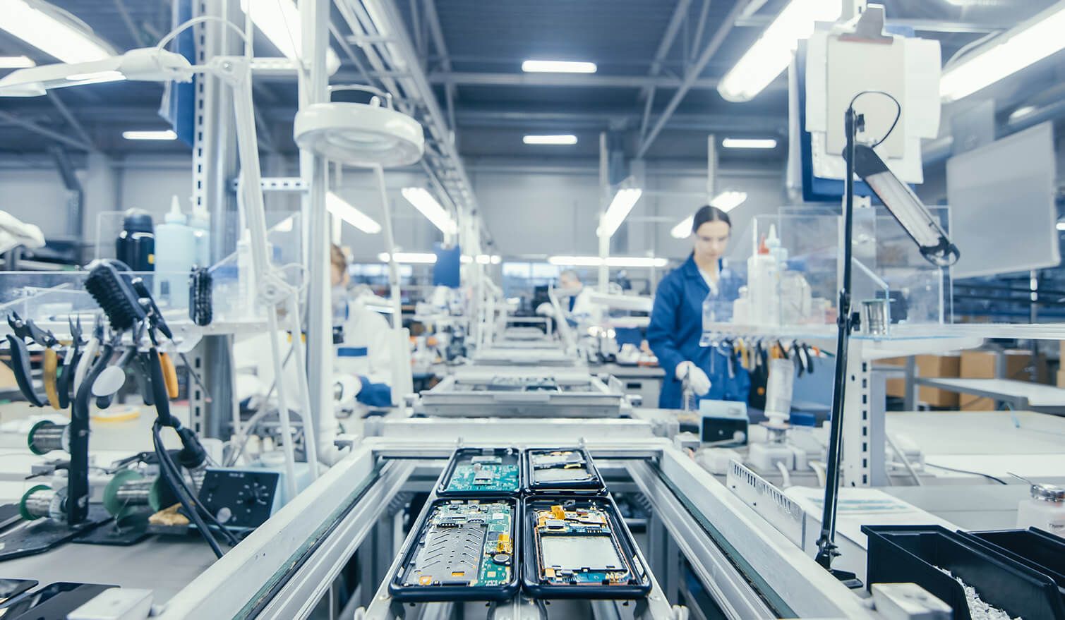 Mitarbeiter in einer Produktionsstätte, die unter entsprechend gestalteter Beleuchtung elektronische Bauteile montieren