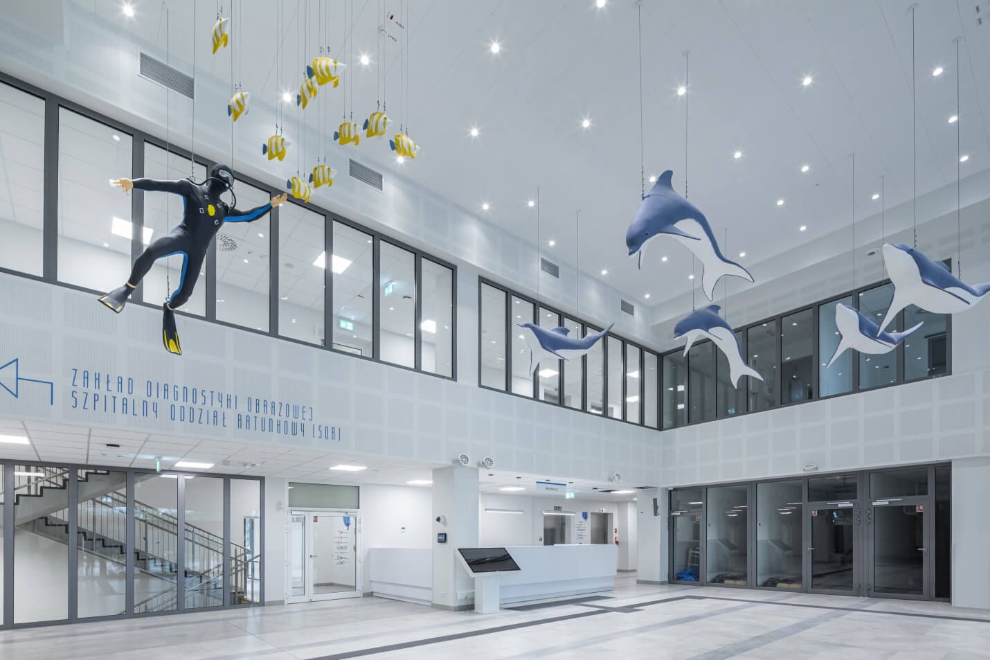 Helles, modernes Krankenhausinterieur mit Rezeption, hängenden Dekorationen in Form von Fischen, Delfinen und einem Taucher sowie moderner LED-Beleuchtung | Lumedic