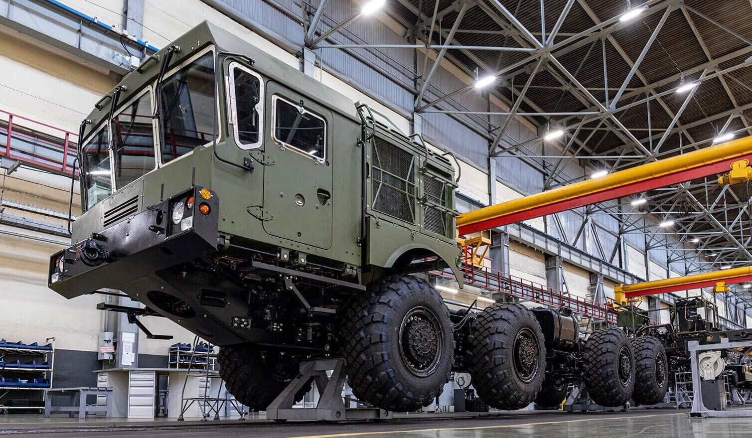 Die Mitarbeiter in der Fabrik arbeiten am Bau eines großen Militärfahrzeugs an einem gut beleuchteten und gut organisierten Arbeitsplatz