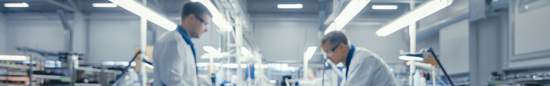 Zwei Männer in Laborkitteln arbeiten in einem modernen Labor an der Herstellung von Elektronik