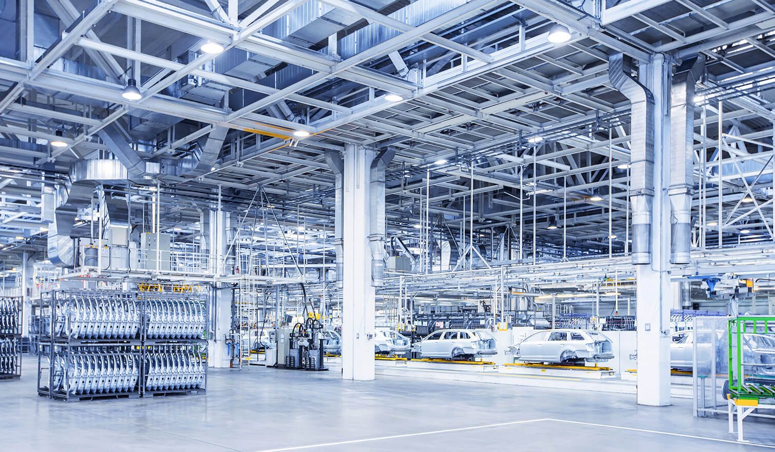 Große Fabrik mit zahlreichen PKWs und LKWs, die die moderne Beleuchtung im Automobilproduktionsprozess zeigt